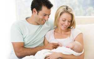 Szkoła rodzenia w Poznaniu "Dobry Początek" - Kobieta trzyma dziecko, blisko niej siedzi mężczyzna